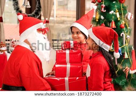 Santa Claus giving gifts to little children 