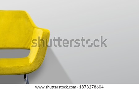 Yellow chair in front of a gray wall. Selective focus. Royalty-Free Stock Photo #1873278604