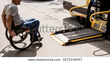 A man in a wheelchair moves to the lift of a specialized vehicle 