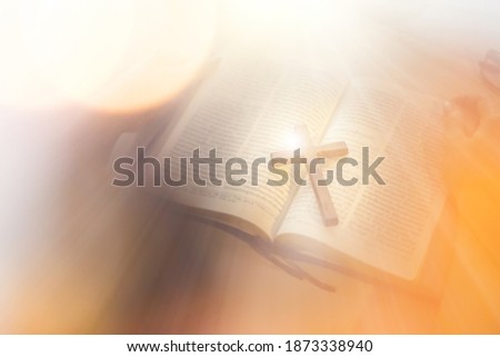 Asian woman praying and holding a cross with her bible on table. Online church from home concept. Royalty-Free Stock Photo #1873338940
