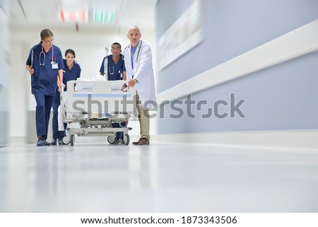 Low angle shot of the Emergency Medical Team Wheeling a Patient Along the Hospital Corridor Royalty-Free Stock Photo #1873343506