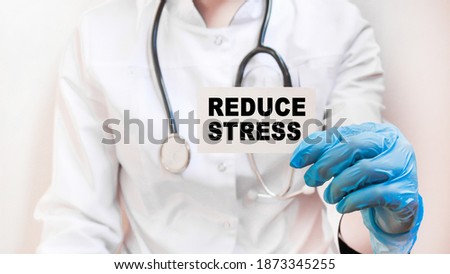The doctor's blue - gloved hands show the word REDUCE STRESS - . a gloved hand on a white background. Medical concept. the medicine