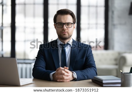 Head shot portrait confident businessman wearing suit and glasses sitting at desk in office, coach mentor shooting webinar, executive making video call to partner, internet meeting, negotiation