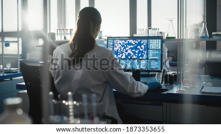 Medical Science Laboratory with Diverse Team of Professional Biotechnology Scientists Developing Drugs, Female Biochemist Working on Computer Showing Gene Therapy Interface. Back view Shot Royalty-Free Stock Photo #1873353655