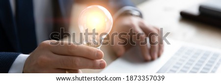 Horizontal banner close up successful businessman holding light bulb, inspiration and creativity concept, innovative business startup idea, motivated executive or boss working on creative project