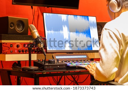 professional sound engineer recording, editing, mixing voice over waveform on computer in post production studio