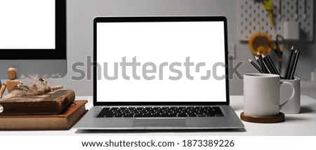 Front view of laptop on creative designer workspace. Blank screen for your information.
