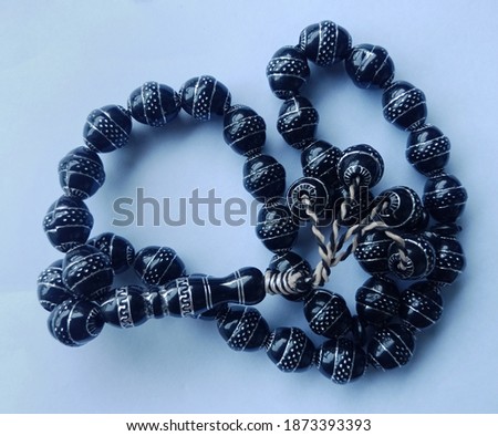Black prayer beads with 33 knots made of stone on a white background
