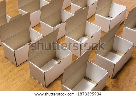 Empty cardboard boxes are stacked in rows. Boxes prepared for packing goods. White open cardboard boxes on a brown background.