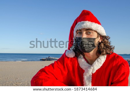 Picture of Young Santa Claus With Black Mask Looking to Camera wit Beach Background in Christmas