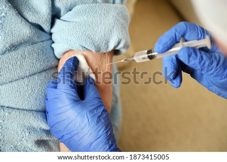 A 90-year-old woman is given the covid-19 vaccine by a doctor. Vaccination of the elderly. Senior woman getting a COVID-19 vaccine at a nursing home. Royalty-Free Stock Photo #1873415005
