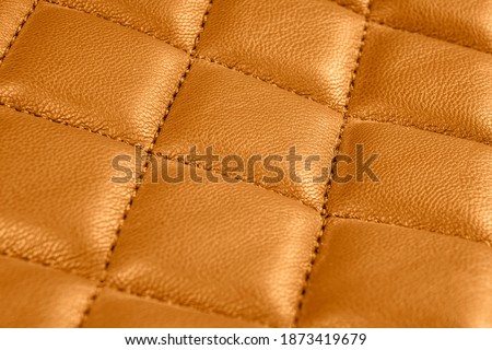 Modern luxury car brown leather interior. Part of perforated leather car seat details. Orange perforated leather texture background. Texture, artificial leather with diagonal stitching. 