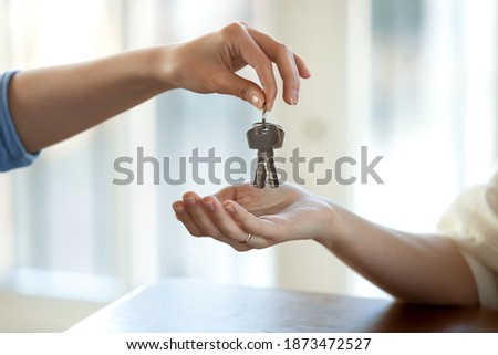Crop close up of real estate agent give hand keys to woman tenant buying first home or apartment. Realtor or broker congratulate female buyer or renter with house rent. Rental, ownership concept. Royalty-Free Stock Photo #1873472527