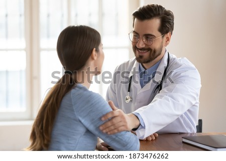 Positive male GP or physician in white medical uniform touch female patient arm show empathy and care. Smiling Caucasian man doctor support woman client at consultation in hospital or clinic. Royalty-Free Stock Photo #1873476262