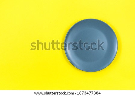 A gray teatka on a bright yellow background. Showcasing the trendy colors of 2021 - gray and yellow. Place for an inscription.