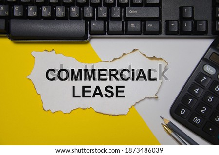 the text commercial lease is white sheet of paper that lies on a computer keyboard and a yellow and white backgroun. High quality photo
