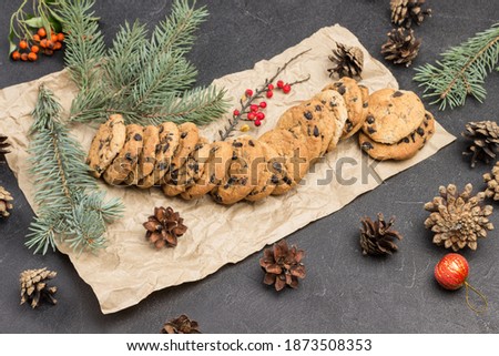 Christmas still life of cookies with cones and fir branches on paper. Black background. Top view. Black background
