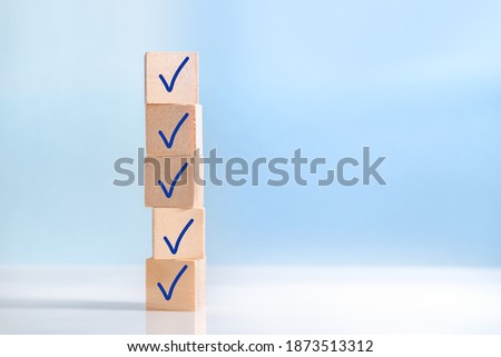 Check mark on wooden blocks, blue background with copy space. Checklist concept Royalty-Free Stock Photo #1873513312