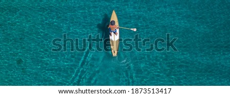 Aerial drone ultra wide photo of fit man practising Stand Up Paddle or SUP in tropical exotic bay with emerald sea