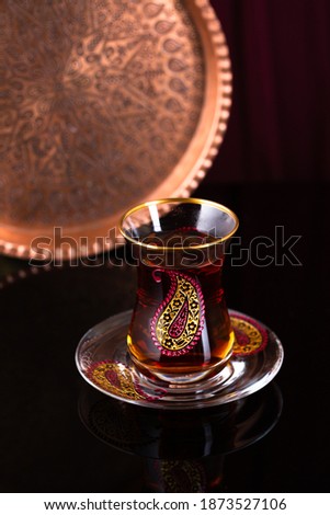 Glass of Turkish tea on black mirror background, beautiful drinkware set of pear shape glasses with fresh tea, national tradition, copy space