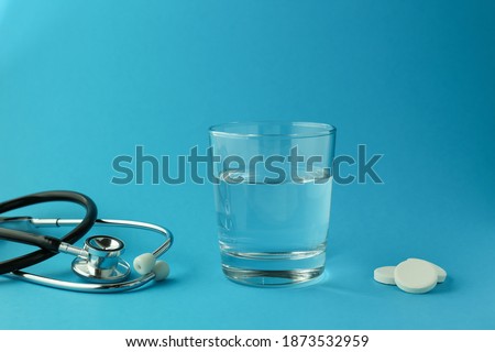 effervescent vitamin C tablet and glass of water on blue background