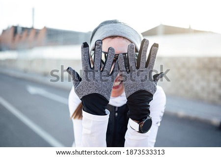 Happy athlete covering face with hands before starting to run