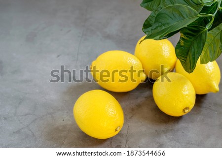 Fresh yellow limons on the grey textured background close up. Top view, copy space. Fresh fruit for healthy eating.