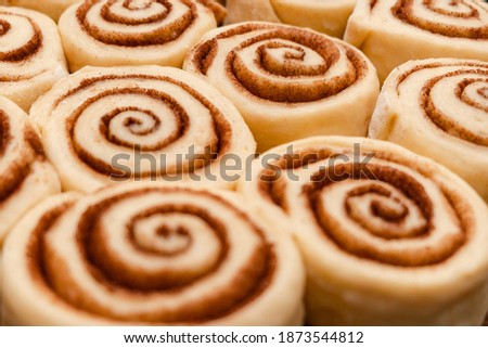 Raw cinnabon buns with cinnamon on ultimate grey backdrop. Christmas bakery. Flatlay. Macro