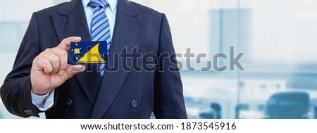 Cropped image of businessman holding plastic credit card with printed flag of Tokelau. Background blurred.