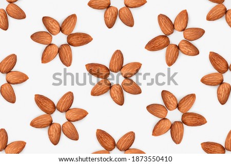 Seamless pattern of almond flowers. 6 raw almonds arranged in a shape of a flower. Concept for health benefits of eating nuts, plant-based diet, or the perfect healthy snack. Isolated on grey.