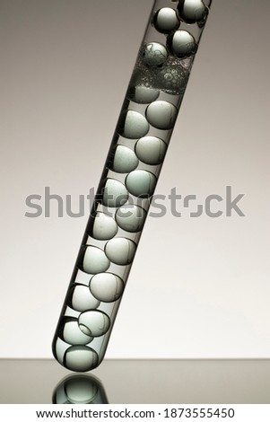 Transparent blue liquid and glass balls in close-up transparent glass test tube