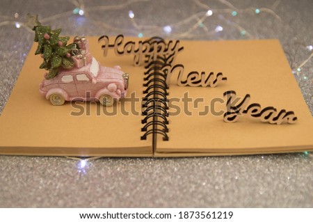 pink car with christmas tree and gifts on open notepad on gray background.new year