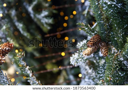 Pine cone on Christmas tree with garland on dark background