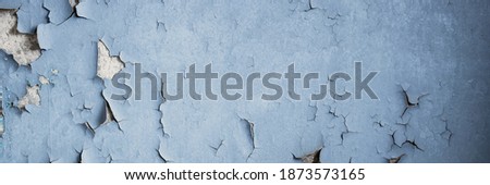 Peeling paint on the wall. Panorama of a concrete wall with old cracked flaking paint. Weathered rough painted surface with patterns of cracks and peeling. Panoramic texture for background and design. Royalty-Free Stock Photo #1873573165