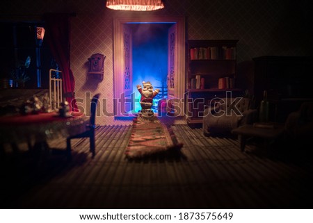 Christmas and New Year holidays concept. A realistic dollhouse living room with furniture and window at night. Artwork table decoration. Santa Claus at the door. Selective focus.