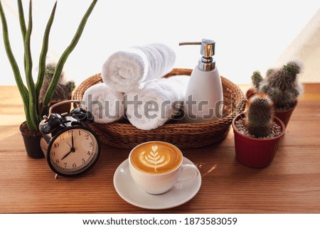 Latte art coffee with Ceramic soap, shampoo bottles and white cotton towels in basket  on wooden table 