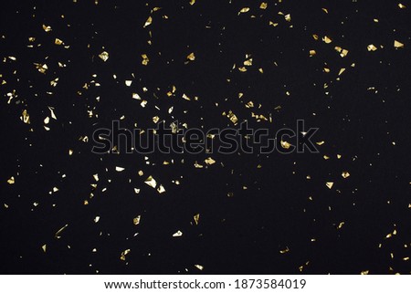 Gold confetti on black background. Festive holiday backdrop. Birthday congratulations Christmas New Year. Flat lay, top view, copy space
