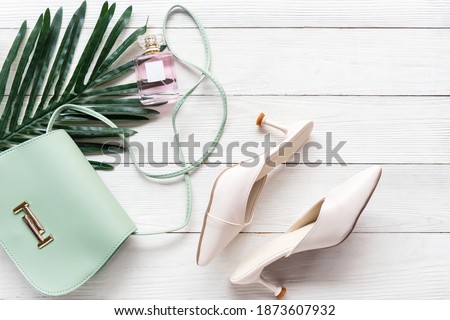 Fashion bag and shoe woman accessories wood white background. Trendy fashion luxury yellow handbag, shoe, perfume and cosmetic design with leave green. Lifestyle and Beauty Concept