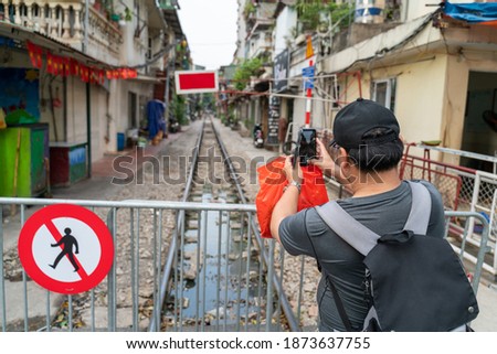 Male tourist taking photo of Hanoi railway next to the "don't walk" sign
