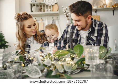 Family sitting on the kitchen. Blonde in a blue shirt. Pregnant woman with her husband and little son