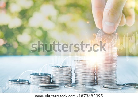 Close up of male hand stacking coins and Trees growing on coin in dark background ,Business Finance and Money, plant growing up on coins and investment budget, saving money investment.concept