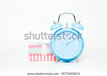 A picture of alarm clock with gift box on white background.