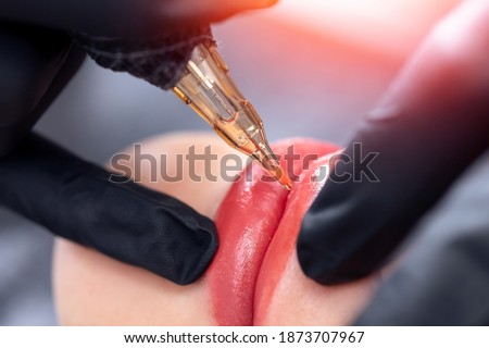 Macro photo of process of applying permanent makeup tattoo of red on lips woman.