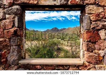 Looking through the window at the picturesque desert landscape from the ruins of a stone house on the Bowen Trail in Tucson Arizona. Royalty-Free Stock Photo #1873712794