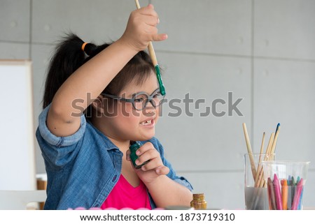 Portrait of young Asian disabled child down's syndrome girl draw a picture with watercolor in element classroom