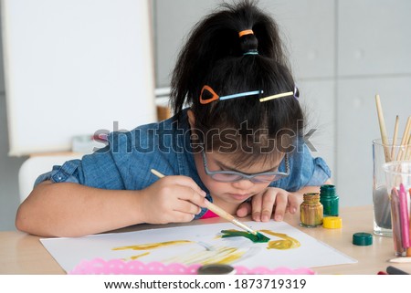 Portrait of young Asian disabled child down's syndrome girl draw a picture with watercolor in element classroom