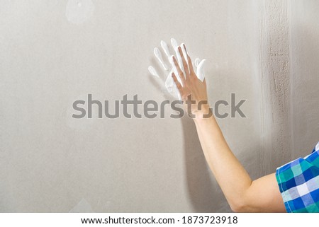 Hand print made with white paint on drywall. painter have fun