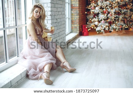 Party, drinks, holidays, people and celebration concept - smiling woman in beautiful dress with glass of sparkling wine and champagne over Christmas tree lights background. High quality photo.