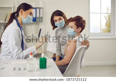 Don't be afraid of injections. Scared child with mum getting jabs at the doctor's office together. Little boy makes funny face when sees syringe needle in nurse's hand during visit to the hospital