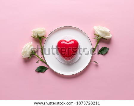red heart cake on white plate and delicate white roses. Concept Valentines Day, Mothers Day, Womens Day. pink background. copy space